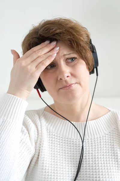 Mujer en auriculares con dolor de cabeza — Foto de Stock