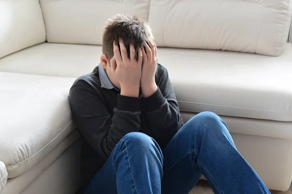 Aufgebrachte Teenager 13 Jahre, sitzt er in der Nähe Sofa bedeckt ihr Gesicht mit ihren Händen — Stockfoto