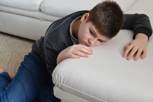 Triste adolescente sentado cerca del sofá —  Fotos de Stock
