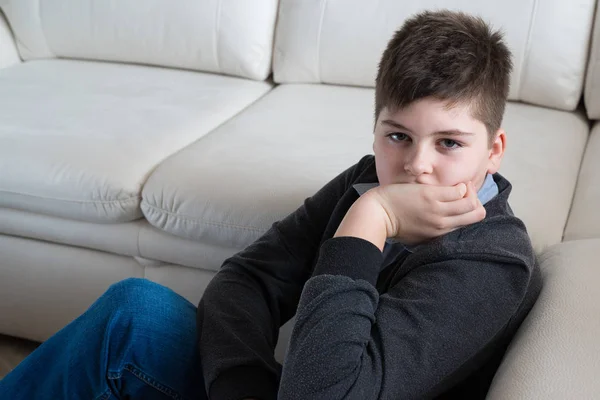 13 ans garçon assis près du canapé dans la chambre — Photo
