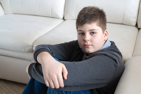 13-летний мальчик сидит возле дивана в комнате — стоковое фото
