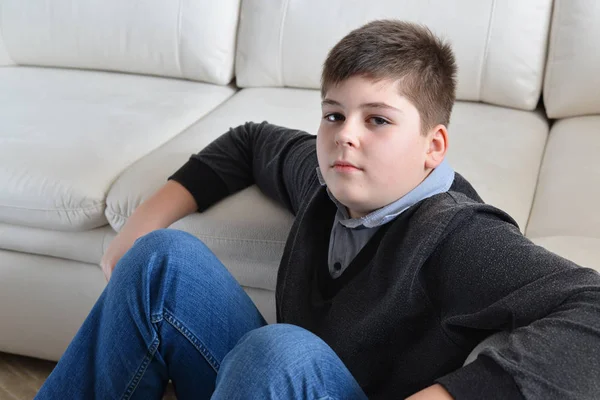 13 year boy sitting near the sofa in room — Stock Photo, Image