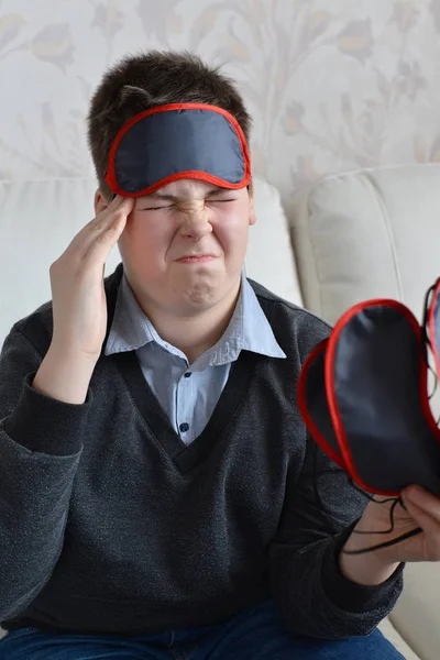 Een tiener met een hoofdpijn in masker voor slaap — Stockfoto