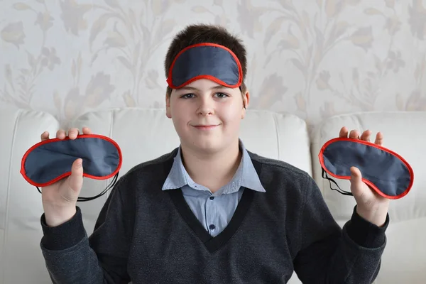 Boy holding a several masks for sleep — Stock Photo, Image