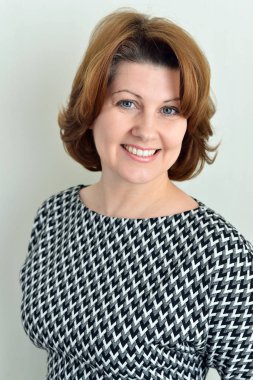 Duvarının yakınında gri elbiseli neşeli kadın