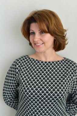 Duvarının yakınında gri elbiseli neşeli kadın