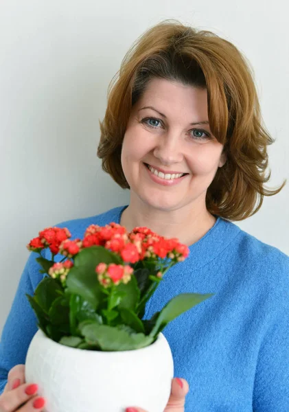 Mujer sosteniendo un kalanchoe rojo en la olla — Foto de Stock