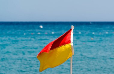 Sahilde deniz arka plan üzerinde kırmızı ve sarı bayrak