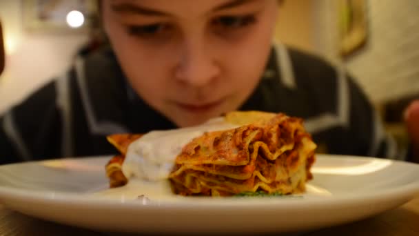 Мальчик в ресторане с тарелкой лазаньи — стоковое видео