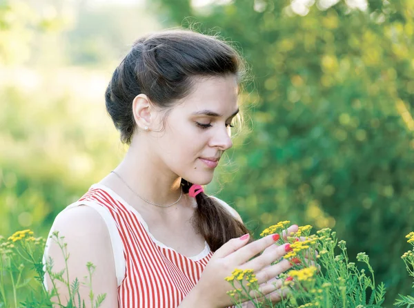 Een meisje kijkt Boerenwormkruid bloemen — Stockfoto