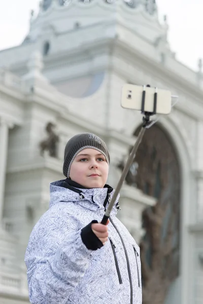 Pojken gör selfie på telefon med selfie stick på bakgrund av sevärdheter — Stockfoto