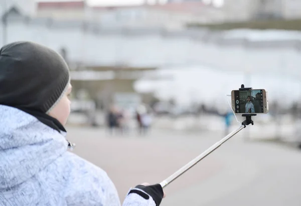 Il ragazzo fa selfie su telefono con bastone di selfie su sfondo di cose notevoli — Foto Stock