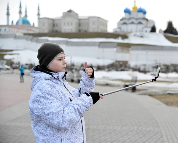 Menino faz selfie no telefone com auto-stick contra pano de fundo de Kazan Kremlin, Rússia — Fotografia de Stock