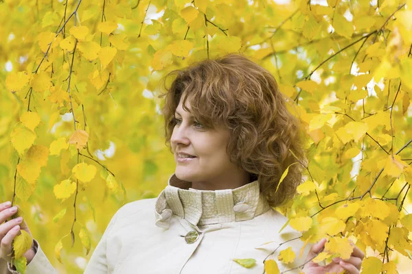 Donna con i capelli ricci vicino betulla autunno — Foto Stock