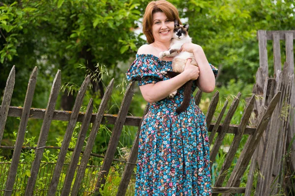 Donna sta tenendo gatto sullo sfondo della recinzione rurale — Foto Stock