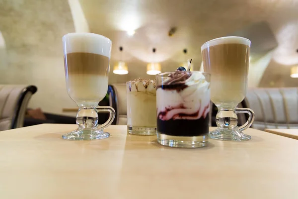 Кофе-латте и десерт со взбитыми сливками на столе в кафе — стоковое фото