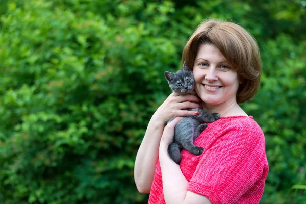 Γυναίκα αγκαλιάζει ένα στενό Σκωτίας μπλε γατάκι σε εξωτερικούς χώρους — Φωτογραφία Αρχείου