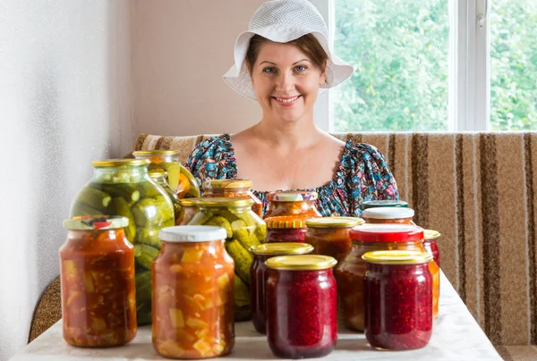 Dona de casa com legumes enlatados e bagas em latas — Fotografia de Stock