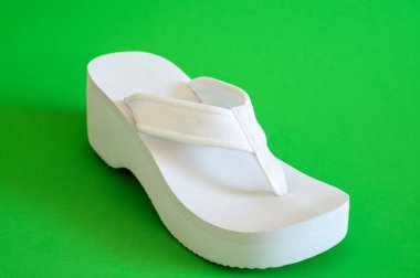 Yeşil arka plan üzerinde beyaz kadın plaj ayakkabı