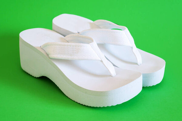 White female beach shoes on green background