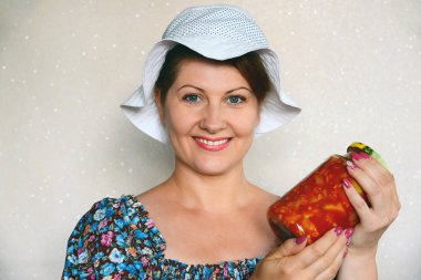 Bir kavanoz kabak ile konserve sebze tutan kadın