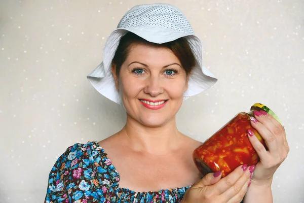 Bir kavanoz kabak ile konserve sebze tutan kadın