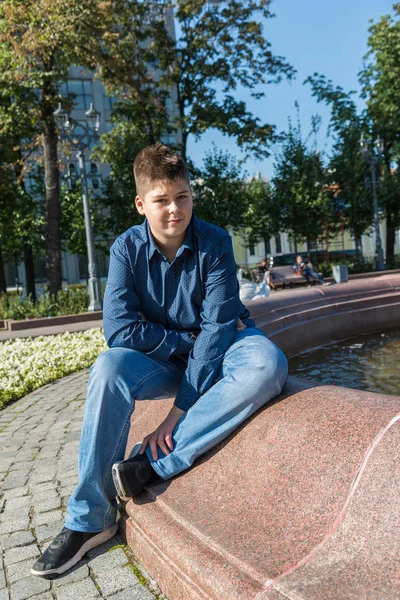 Adolescente di 14 anni è seduto vicino alla fontana — Foto Stock