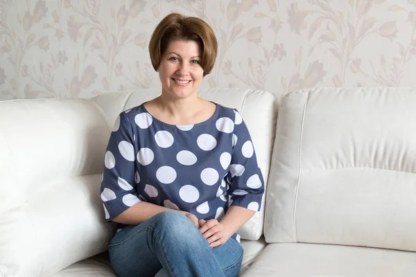 Женщина сидит на белом диване в комнате — стоковое фото