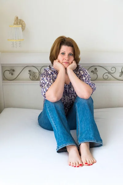 Frau sitzt im Schlafzimmer auf Bett — Stockfoto