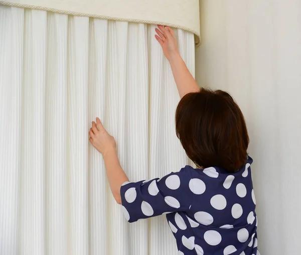 Žena visí bílé záclony na okně v bytě — Stock fotografie