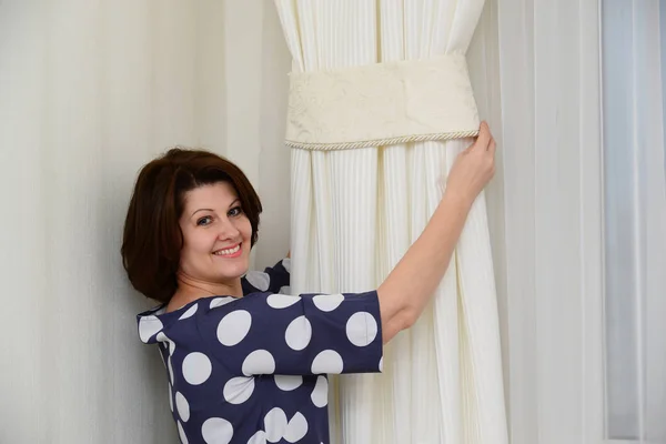 Mujer pone abrazaderas en las cortinas — Foto de Stock