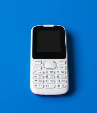 Düğmeli mavi zemin üzerine beyaz cep telefonu.
