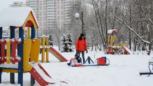 Moskau, Russland - 4. Februar. 2018. mama rollt ein baby auf dem karussell im winter — Stockvideo