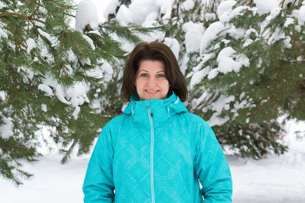 Kvinnan i blå sport jacka i snötäckta fir skog — Stockfoto