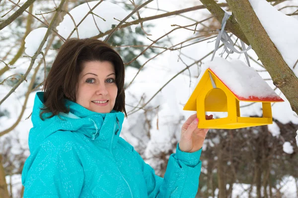 Woman stands near yellow bird feeder — Stock Photo, Image