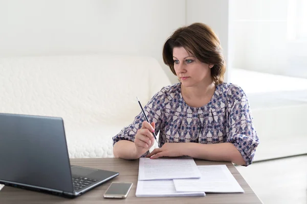 Kobieta w pracy z dokumentami patrząc na laptopa — Zdjęcie stockowe