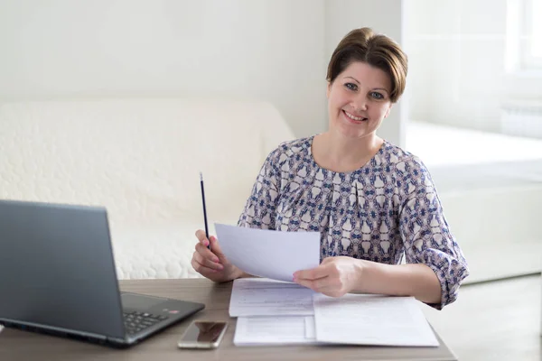 Vrouw die werkt met documenten kijken naar laptop — Stockfoto