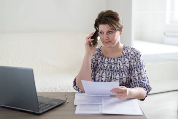 Frau arbeitet mit Dokumenten und telefoniert — Stockfoto