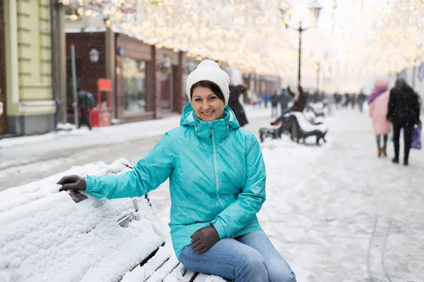 女性は、ロシアのモスクワの通りの雪に覆われたベンチに座っています。. — ストック写真