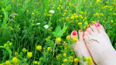 Yeşil çimenlerin üzerinde kırmızı bir pedikür ile bakımlı kadın bacakları