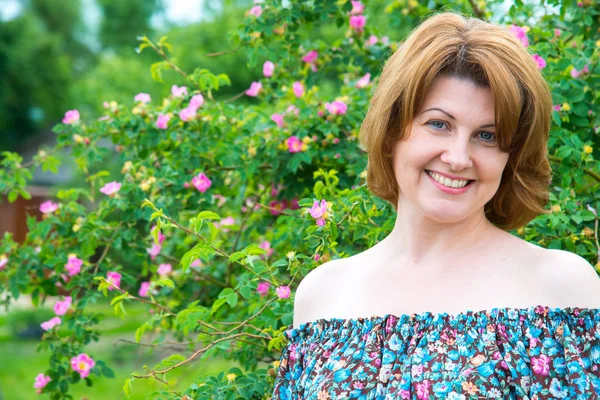 Portrait de belle femme sur fond de rose sauvage en fleurs — Photo