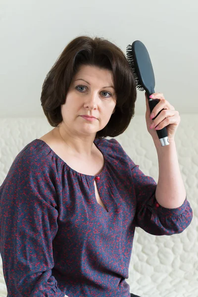 Woman with a massage comb brushes her hair — Stock Photo, Image