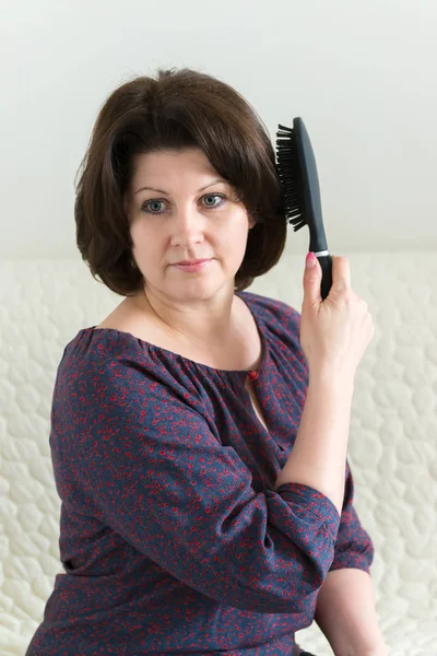 Frau mit Massagekamm bürstet sich die Haare — Stockfoto