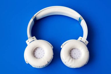 mavi zemin üzerine beyaz kablosuz bluetooth kulaklık