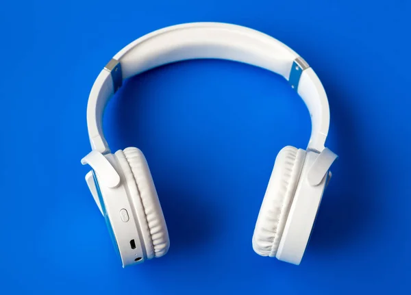 White wireless bluetooth earphones on blue background — Stock Photo, Image