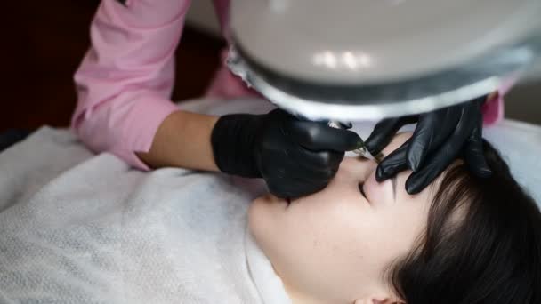 Mestre faz a tatuagem em sobrancelhas para menina . — Vídeo de Stock