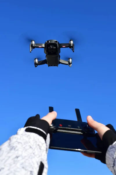 Quadrocopter flies in sky and hands with a control panel. — Stock Photo, Image