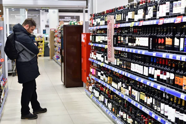 Moskva, Ryssland - 18 mars. 2018. mannen ser på rött vin i Perekrestok butik — Stockfoto
