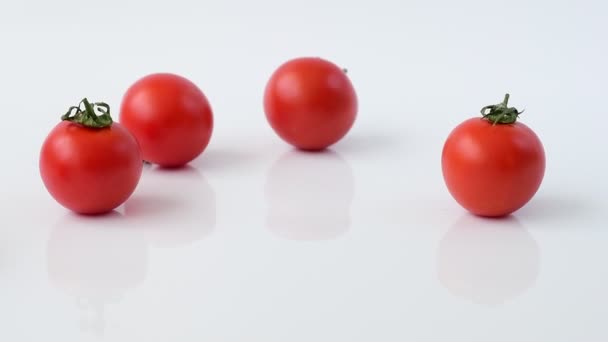 Tomatoes roll on white background in slow motion — Stock Video