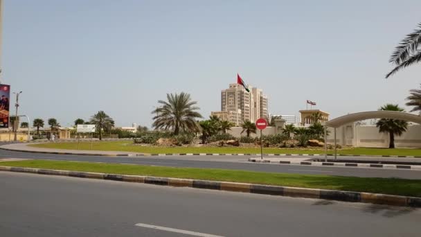 Ajman, Egyesült Arab Emírségek - április 11-én. 2018. a tipikus városkép road és a zászló. — Stock videók